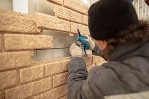 man installing brick siding