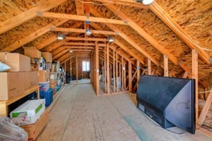 interior of the attic of house with boxes and old appliances under gable roof